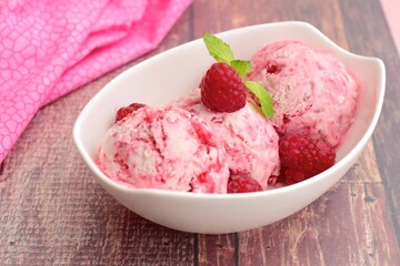 Scoops of raspberry ice cream in a bowl garnish with mint leaves. Summer dessert