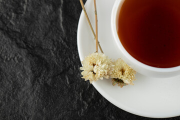 A cup of tea with dried flowers on a black background