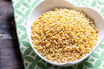 Dry ptitim close-up. Toasted pasta ptitim (petit plomb or Israeli couscous)  on a wooden background.