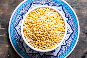 Dry ptitim close-up. Toasted pasta ptitim (petit plomb or Israeli couscous)  on a wooden background.