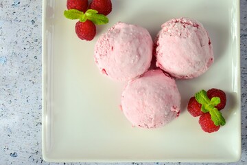 Scoops of raspberry ice cream garnish with mint leaves. Summer dessert