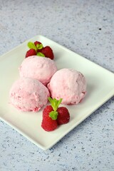Scoops of raspberry ice cream garnish with mint leaves. Summer dessert