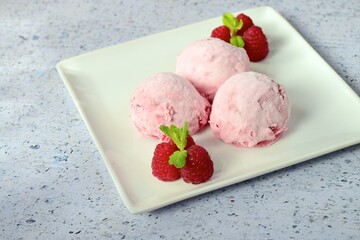Scoops of raspberry ice cream garnish with mint leaves. Summer dessert