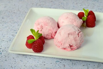 Scoops of raspberry ice cream garnish with mint leaves. Summer dessert
