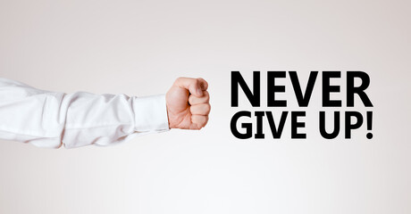 Male arm with hand as a clenched fist points towards the motivational message never give up.