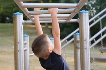 Fototapeta premium boy, kid walking on an incline on the playground, rear view, concept of physical activity, children's sports, balance