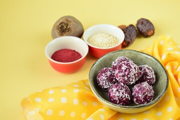 Beetroot quinoa date almond coconut energy balls on yellow background