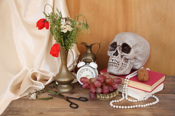 wildflowers, poppies in an old brass jug on an old wooden table, skull, alarm clock, books, grapes,...