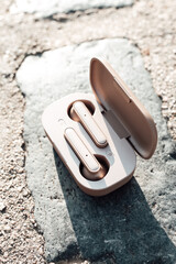 True wireless earbuds in case on natural stone background, top view,closeup, copy space