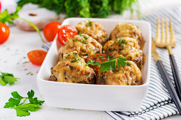 Baked mushrooms stuffed with chicken minced meat, cheese and herbs on light plate.
