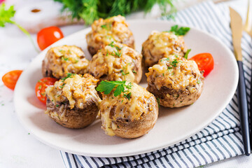Baked mushrooms stuffed with chicken minced meat, cheese and herbs on light plate.