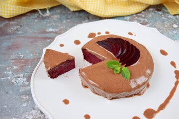 Homemade gluten free vegan beetroot chocolate cake with almond butter topping garnish with hemp seeds, mint leaf and sliced beetroot. 