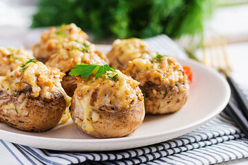 Baked mushrooms stuffed with chicken minced meat, cheese and herbs on light plate.