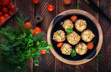 Baked mushrooms stuffed with chicken minced meat, cheese and herbs on a wooden background. Top view, above, copy space