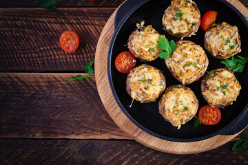 Baked mushrooms stuffed with chicken minced meat, cheese and herbs on a wooden background. Top view, above, copy space