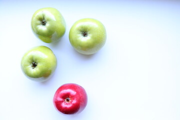Three green and one red apples on a white background 