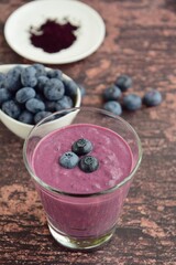 Fresh blueberry smoothie in a glass on wooden background. Selective focus