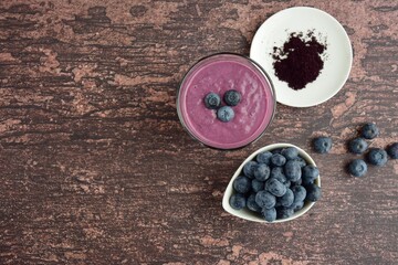 Fresh blueberry smoothie in a glass on wooden background. Flat lay