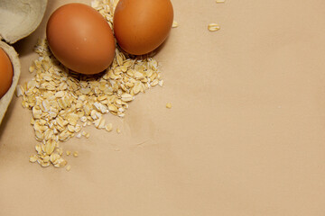 Chicken eggs and oatmeal on a beige background with a place for text, healthy food, natural...