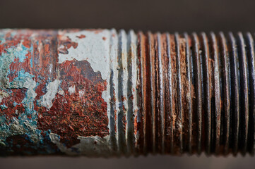 plumbing old rusty water pipe with remnants of sealant and tow on worn threads, peeling paint, selective shallow depth of field