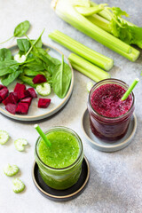 Vegan diet and nutrition, healthy detox, vegetarian concepts drinks. Beet smoothie and Green smoothie celery and spinach on a gray stone countertop.