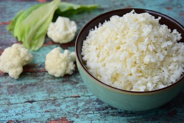 Cauliflower rice on green wooden background, selective focus
