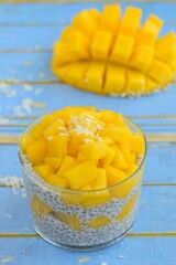 coconut mango chia seed pudding on blue wooden background
