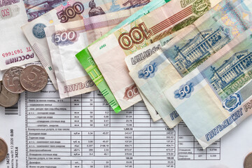 Russian money, a piece of paper with numbers on top of a receipt for payment of utilities. Background with Russian accounts for payment and rubles.
