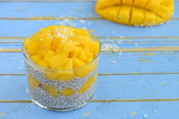 coconut mango chia seed pudding on blue wooden background
