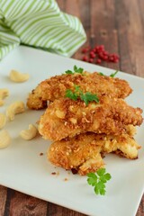 Chicken fingers or chicken strips breaded with cashew and coconut flakes garnish with parsley