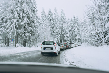 Fototapeta na wymiar Traffic jam on a snow-covered road. Cars keep their distance.Family trip, vacation, adventure. Winter landscape. Driving a car in extreme winter conditions.Travel concept background