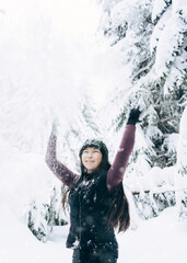 Fototapeta na wymiar Young happy girl is enjoying the winter on a frosty day, with snow playing with snow in winter Park.The winter lifestyle.Individual winter adventures.Rest during the Christmas holidays.healthy break