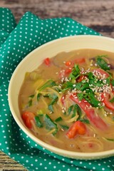 Gluten free chickpea noodles soup with spinach, red bell pepper and bok choy garnish with parsley and sesame seeds
