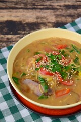 Gluten free chickpea noodles soup with spinach, red bell pepper and bok choy garnish with parsley and sesame seeds
