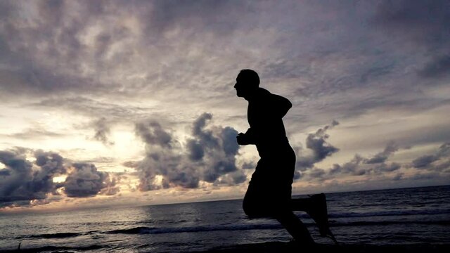 Young man jogging on the beach during sunset, super slow motion, shot at 240fps
