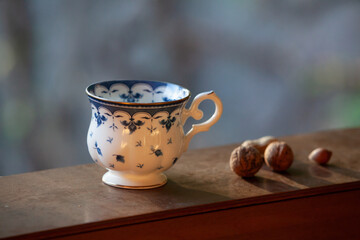 Elegant tea cup and walnuts stand on shelf