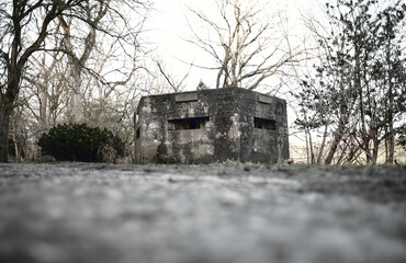 A brutalist cold gritty concrete world war two, ww2, pillbox war bunker defence fortress in a dirty forgotten woodland in europe. wartime relics and forgotten outpost using solid architecture