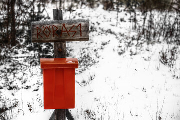 Archaic street sign with a red mailbox in snow