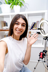 Mixed race influencer girl blogger taking picture of herself, selfie,preparing for a live broadcast video blog on social network at home.Social media live streaming concept.