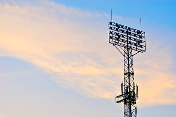 Silhouette of a spotlight with television antennas on a sunset background. Lamps for stadium...