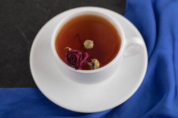 Dried rose in a cup of hot tea on a black background
