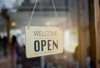 A wooden sign hanging in front of a mirror at the entrance of the coffee shop Concept of opening shop in the morning
