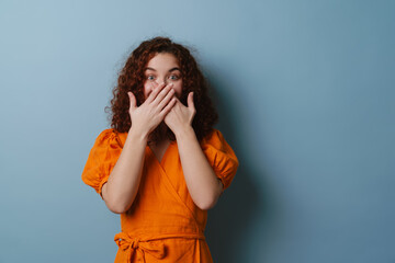 Redhead excited girl looking at camera and covering her moth