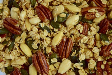 Making of homemade granola made from oat, almond, pecan nuts, pumpkin seeds and maple syrup