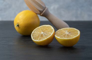 Fresh yellow sliced and whole lemons with a wooden reamer