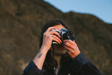 Portrait of young millennial woman practice making photos on analog film camera. Analog photography...