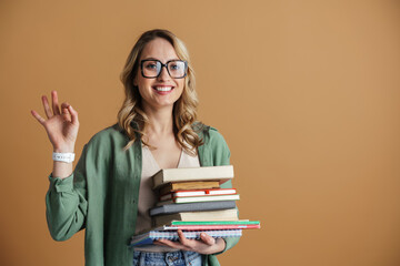 Happy woman showing ok sign while posing with books and planners