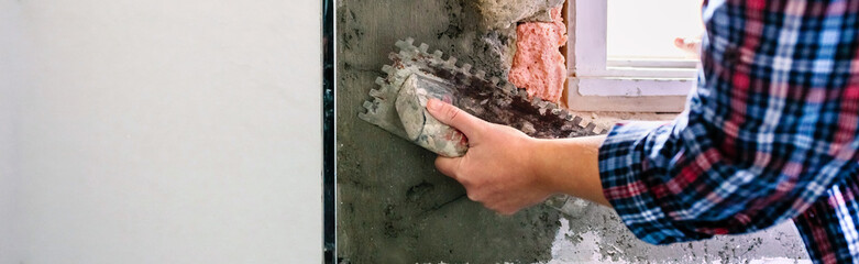 Unrecognizable bricklayer hand leveling cement with a trowel to tile the wall