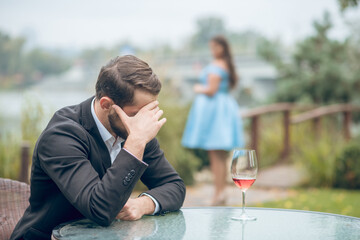 Unhappy man at table and woman in distance