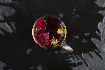 Dried rose in a cup of hot tea on a black background